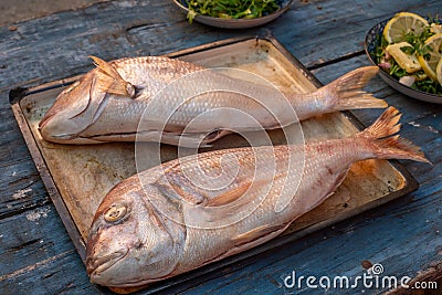 High-angle shot of two â€‹â€‹breams with cut stomachs on a tray on a wooden kitchen table Stock Photo
